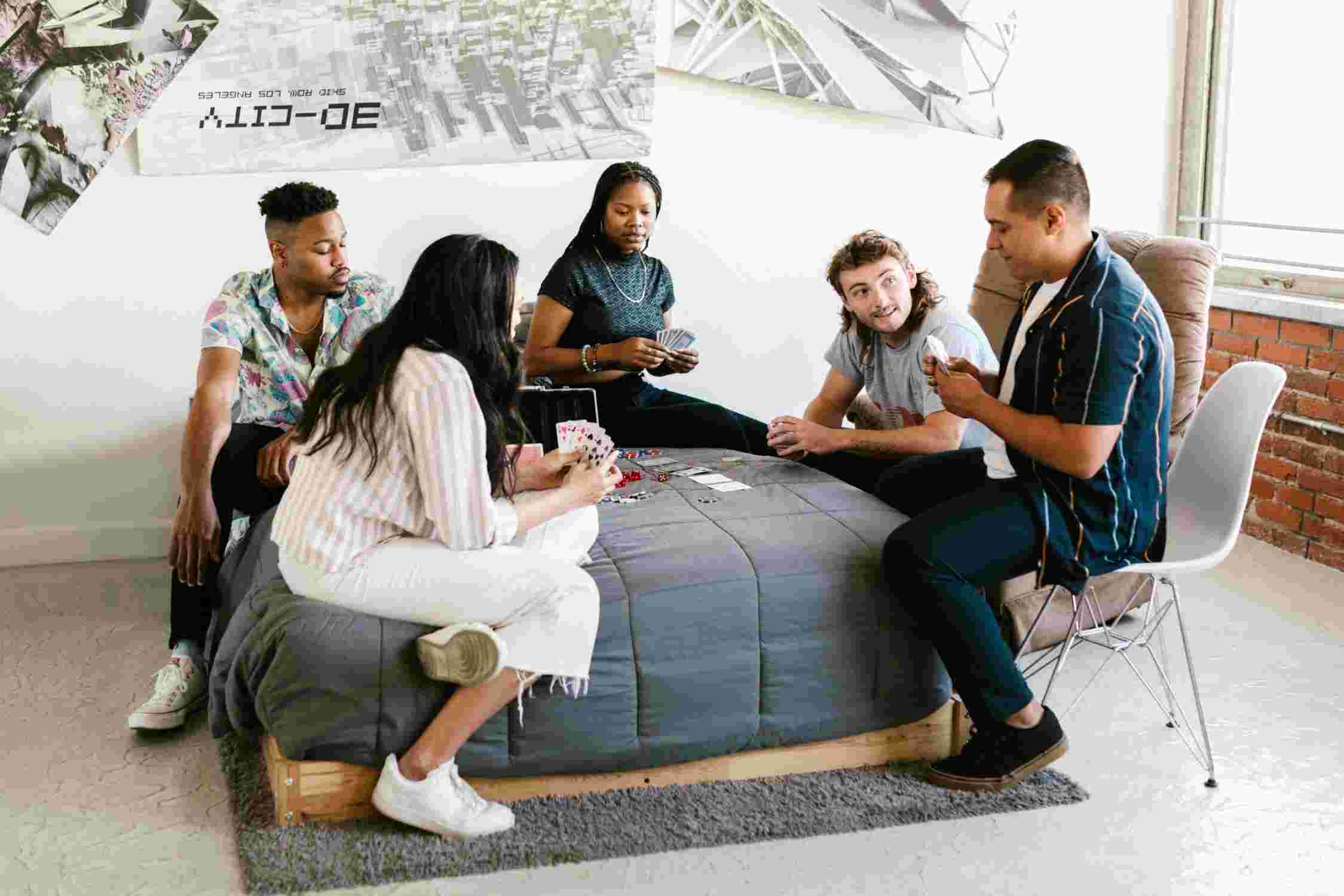 Fünf ausländische Studierende, die auf einem Sofa ein Kartenspiel spielen.