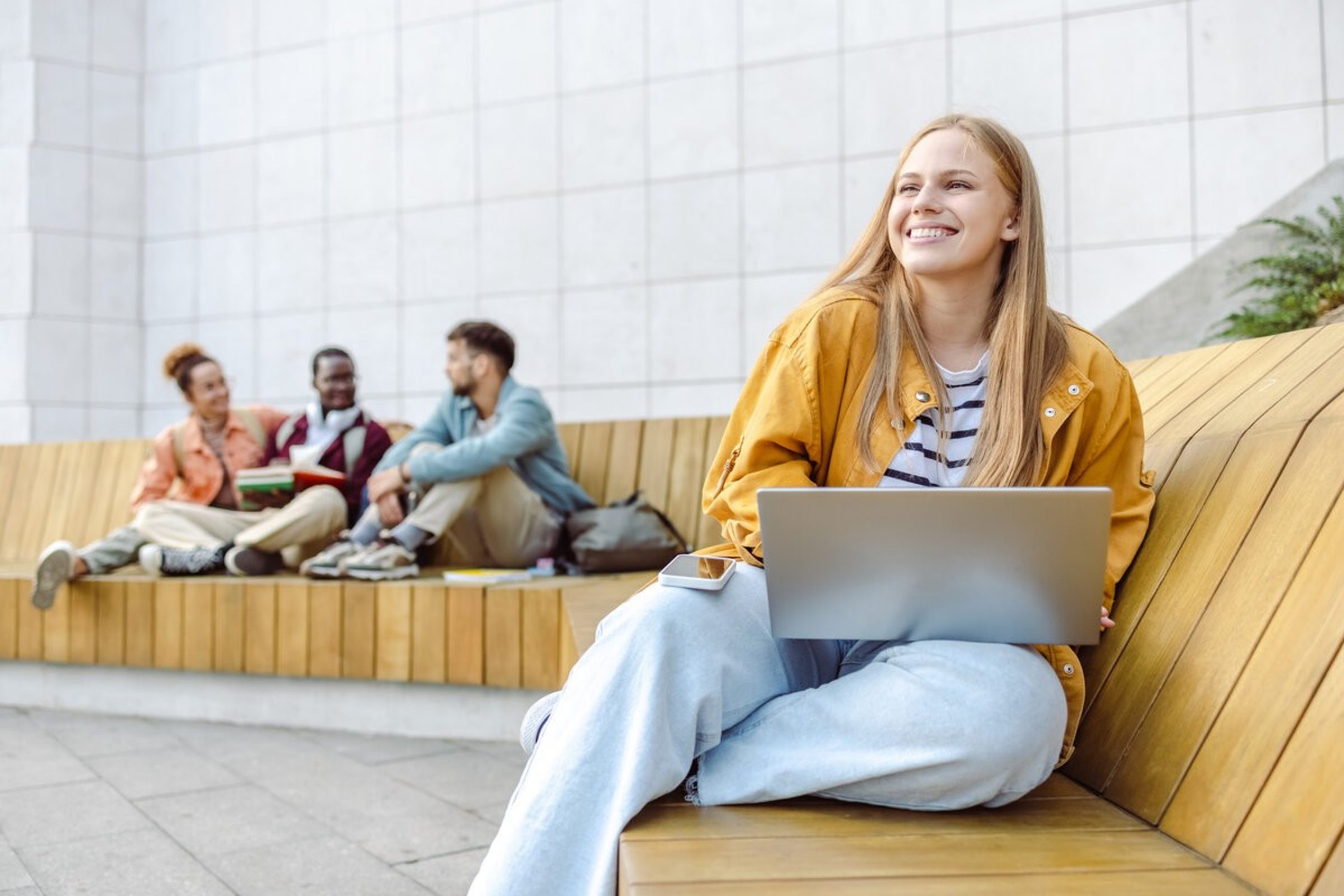 Woman sitting on a bench with a laptop.