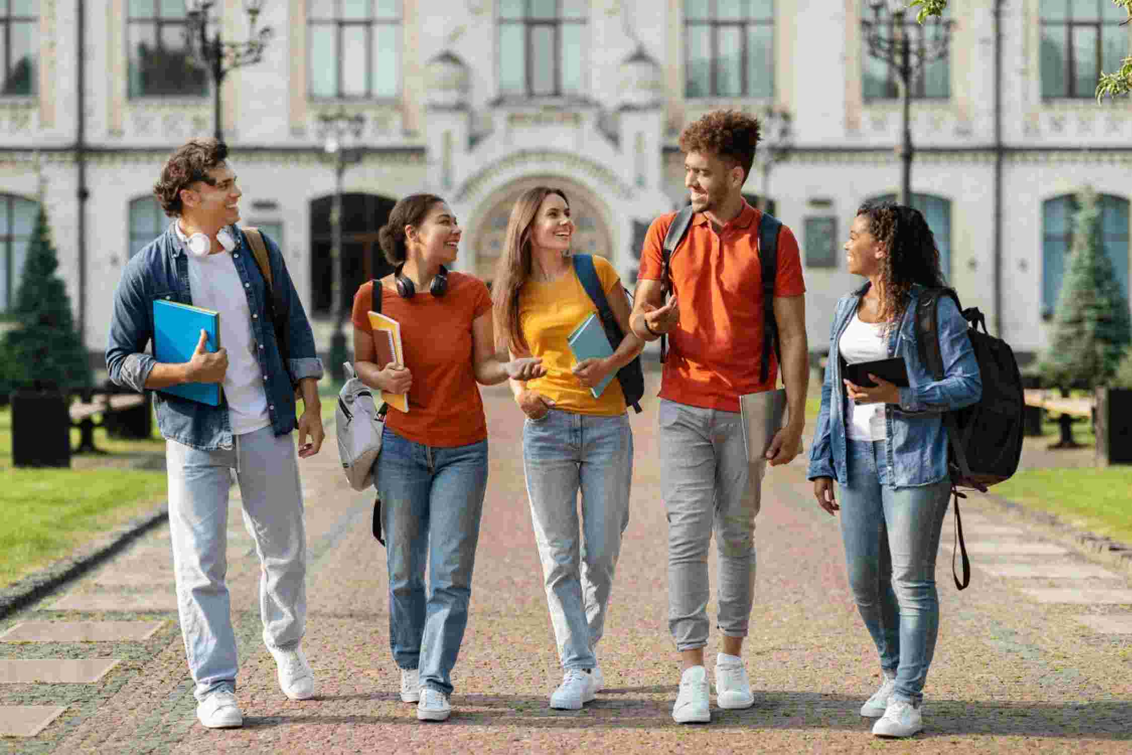 Eine Gruppe internationaler Studierende laufen zusammen durch den Campus und halten Bücher in den Händen.