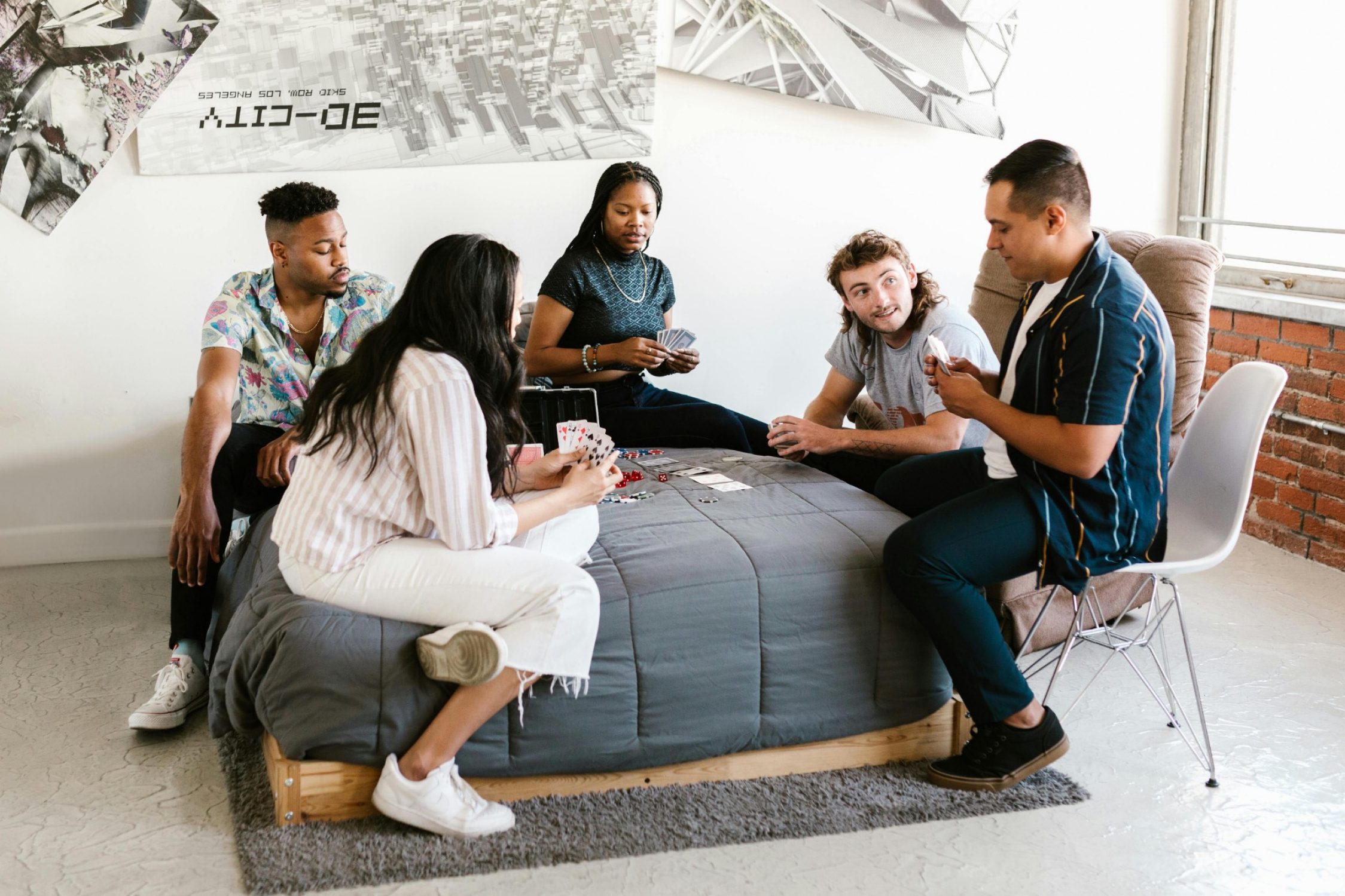 Five foreign students playing a card game on a couch.
